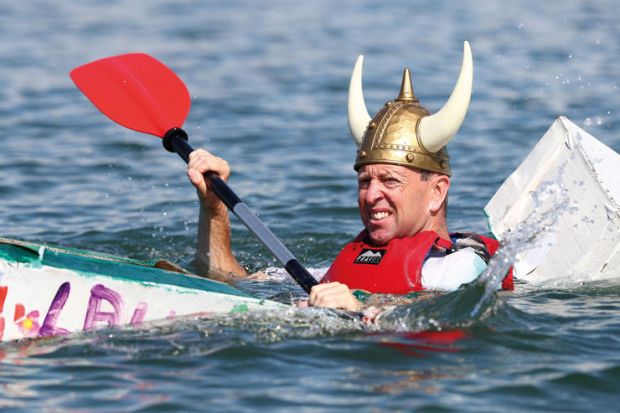 Person wearing viking hat in a cardboard boat sinking at a boat Regatta to illustrate the Danish humanities courses pressed on contact hours as funding cut