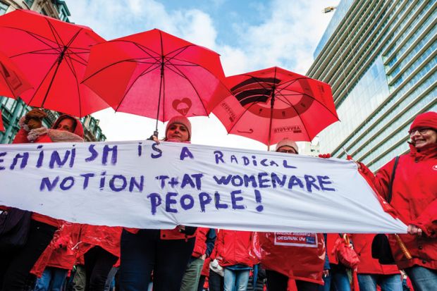 A group of women are holding a feminist placard while holding red umbrellas, during the National demonstration for better social security, in Brussels 