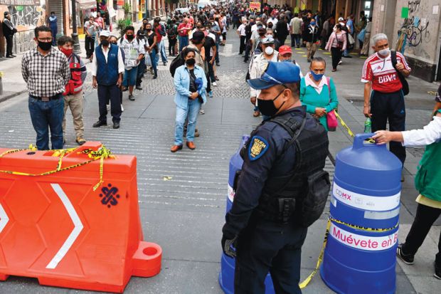 Police and city government workers stand at a pedestrian control that limits the access in groups of 20 people to enter downtown Mexico City 