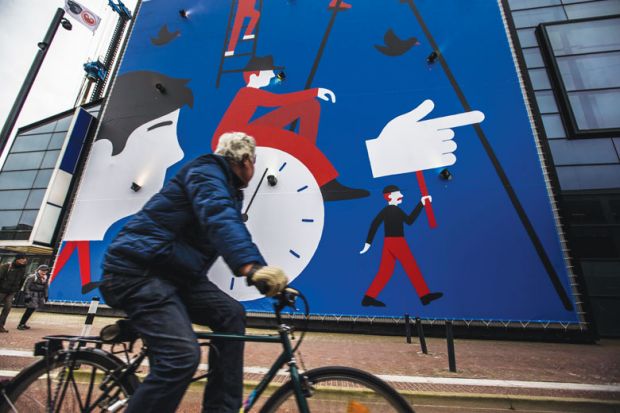 A man rides a bicycle past a wall painting