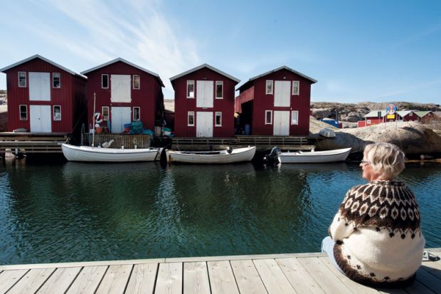 Woman relaxing on jetty and looking at a row of boat houses in Sweden to illustrate Autonomy concerns as Sweden consolidates research funders