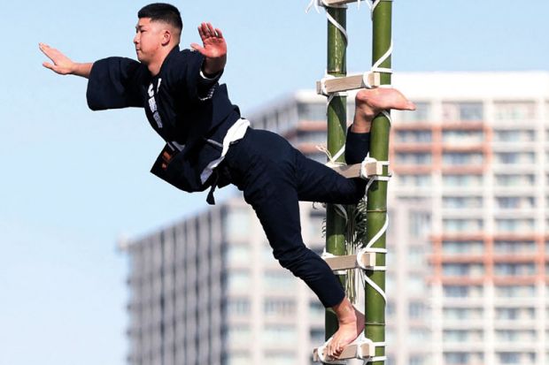 Performer balances on the top of a bamboo ladder to illustrate Japan’s ¥10 trillion excellence fund off to shaky start