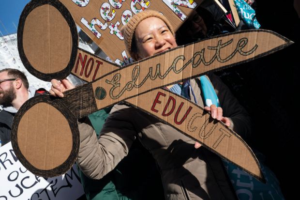 UCU member holding a cardboard banner of a pair of scissors to protest against cuts to illustrate UK sector at ‘rock bottom’ as pay dispute derails graduations