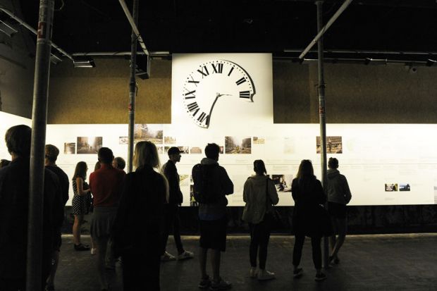 Visitors stand in front of of a 17-metre timeline of events including a clock face in Oslo, Norway to illustrate Norway nervous as international student fee deadline looms