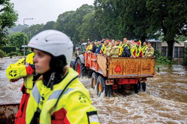 People are being evacuated in a tractor trailer in a flooded street as a metaphor for  Europe mulls ‘war games’ to brace for future crises