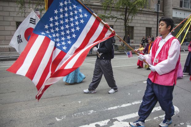 Annual Korean Day Parade man holding American flag to illustrate ‘High stakes’ and hurdles ahead for KAIST’s New York campus