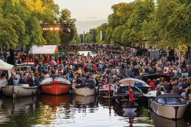 Crowds on boats gather towards a floating stage on the Prinsengracht to illustrate Dutch plead for limits on international recruitment