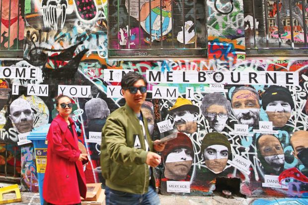 People walk past walls adorned with graffiti in Hosier Lane, one of Melbourne's iconic laneways to illustrate Staff at an Australian university who refer to colleagues using unfavoured pronouns could find themselves facing disciplinary proceedings 