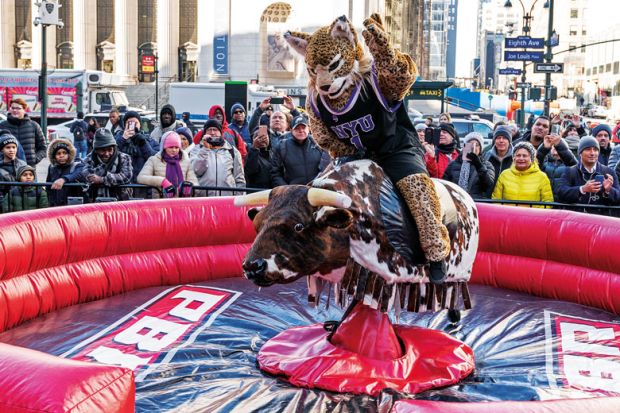  NYU mascot The Bobcat rides mechanical bull to illustrate xecutive search firms blamed for shrinking presidential tenures