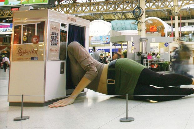 A giant statue of a female figure sprawled across Victoria train station's concourse, her upper body squeezing into a photobooth as a metaphor for the Treasury using a lower cap to reduce the outlying on student loans.