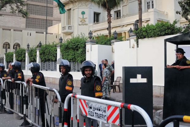 Egyptian security forces stand guard outside the Saudi embassy as a metaphor that a University of Washington doctoral student is being detained in Egypt.