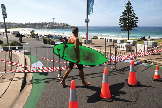 A surfer walks past the entrance to the car park to Bondi Beach which is blocked as a metaphor for research grant veto powers need guidance, say scholars