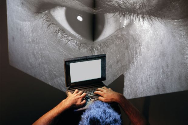  Man sits at laptop computer with image of giant eye on a big screen as a metaphor to show the online behaviour of Eric Chabriere.