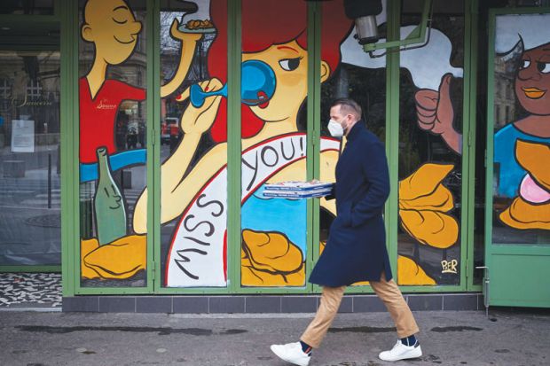Image of a man swalking past a closed restaurant with a miss you illustration on the shop window