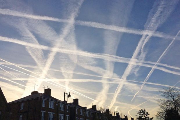A pattern of condensation trails produced by aircraft engine exhausts, criss-cross the sky to illustrate Fragility in the system