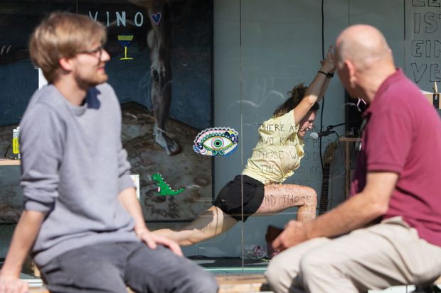 Two people watching an artist doing yoga in a container