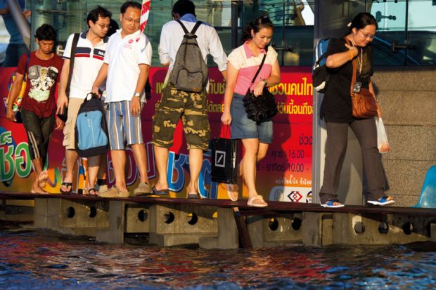 Bangkok commuters head home negotiating a narrow walkway through heavily flooded downtown streets
