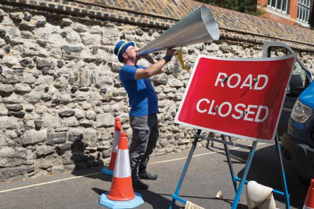 Man shouts through his oversized megaphone with stop road sign in front of him to illustrate English free speech bill stalls but ministers ‘remain committed