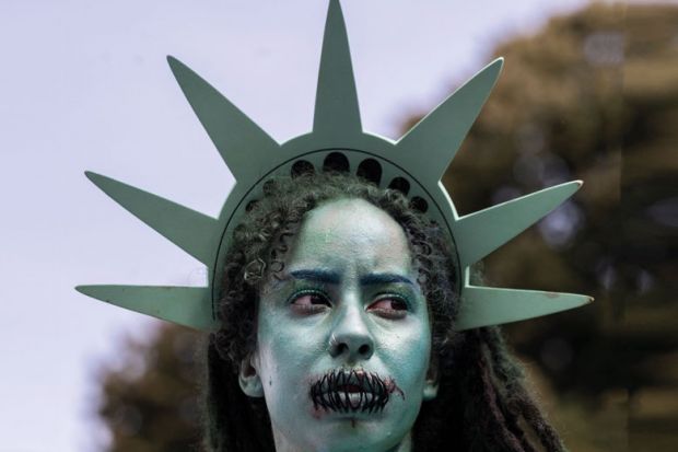 A protester dresses as the Statue of Liberty with stitches over her mouth to illustrate Chicago Principles put to the test in US