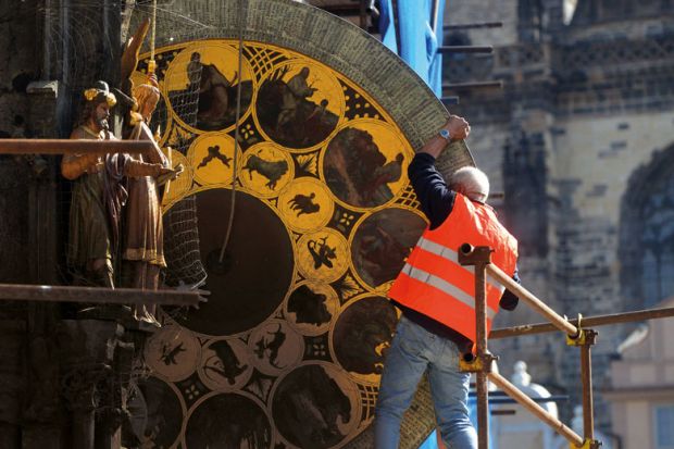 Worker removes the calendar dial of Prague's medieval astronomical clock  to illustrate Feared Czech institute takeover risks ‘incompetent interference’