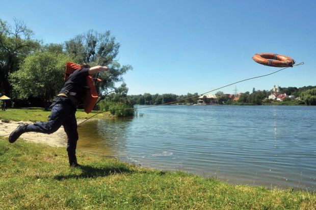 A rescuer throws a lifebelt into a lake