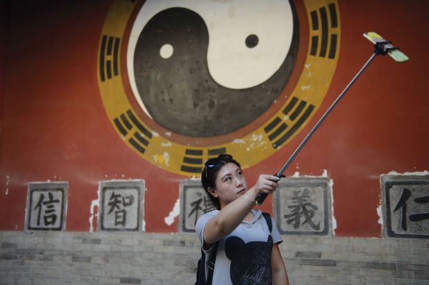 A tourist takes a selfie stick while visiting an ancient palace in China