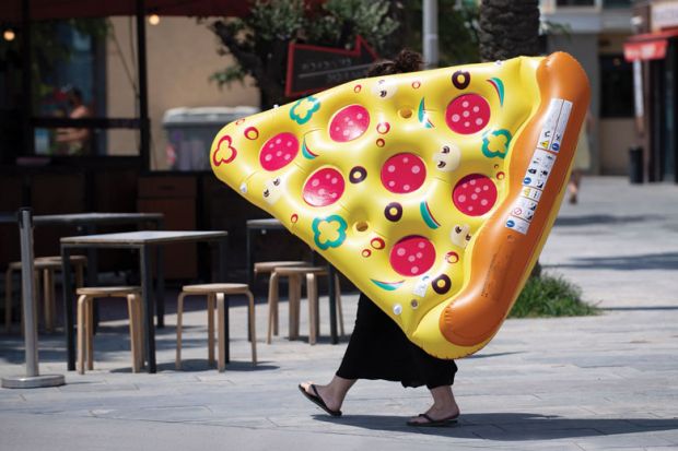 A woman carries an inflatable float with the shape of a portion of pizza 