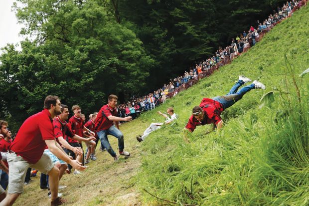 a competitor comes tumbling down the hill during the cheese rolling competition near the village of Brockworth, Gloucester, in western England