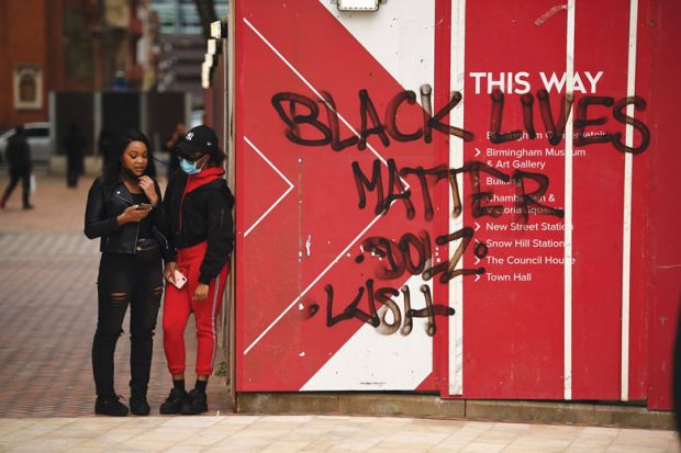 two people stand stand beside Black Lives Matters graffiti 