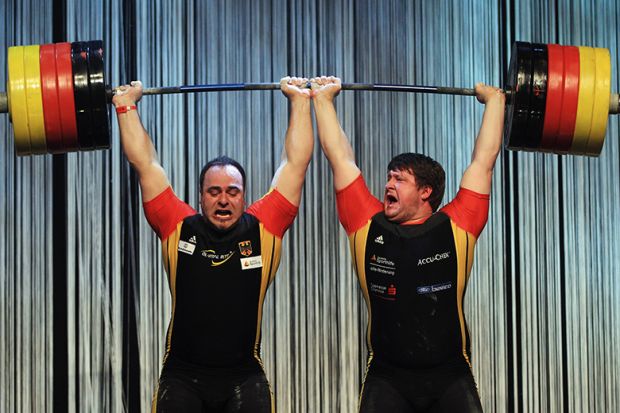 Weightlifters holding a bar over their heads symbolising new powers granted to PhD students to combat bullying and overwork