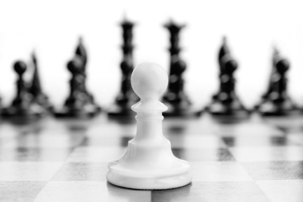 White chess pawn with black pieces in background