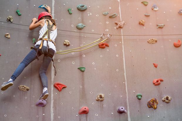 Woman representing a PhD student climbing in an indoor climbing centre