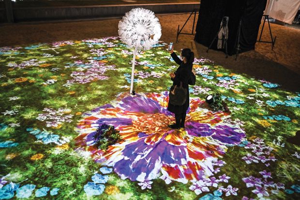 A woman uses her smartphone in an interactive multimedia installation that connects Singapore and Japan in a time of separation, in Tokyo on November 13, 2020