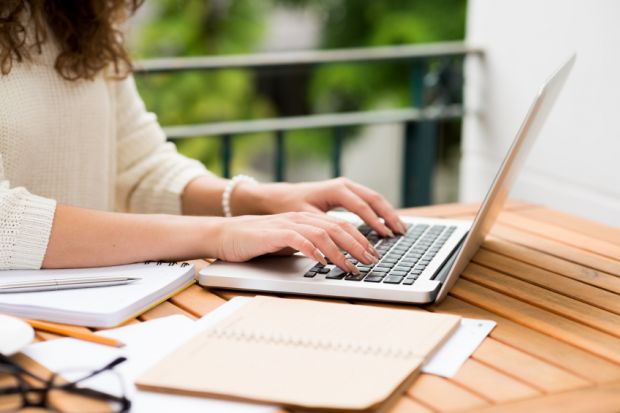 Woman writing using laptop computer