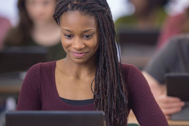 Young female student smiling and looking at computer monitor Young female student smiling and looking at computer monitor