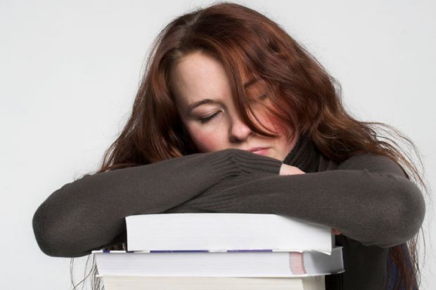 Young woman asleep on pile of books