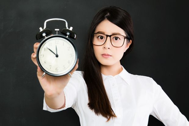 Young woman holding old alarm clock