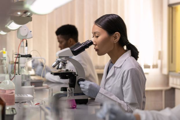 Young female scientist looking in microscope