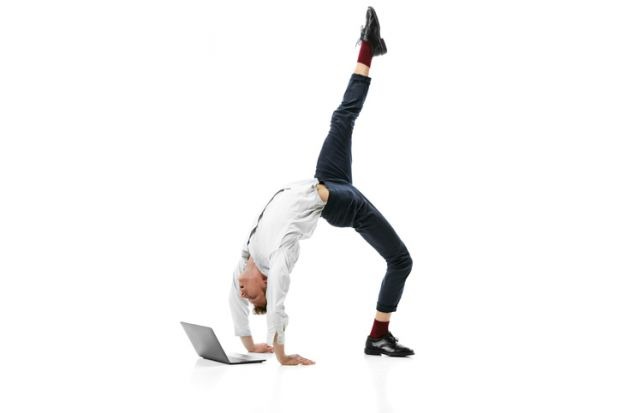 young flexible man doing backbend and typing on laptop