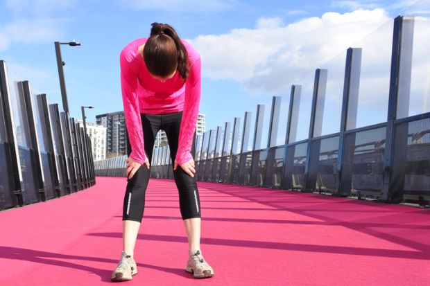 Young woman exhausted after running on a bright pink cycleway road in Auckland, New Zealand.