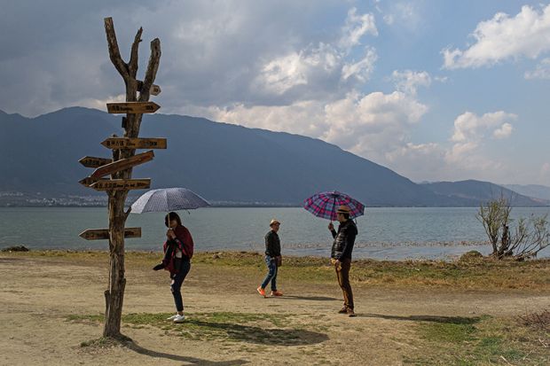 Tourists with umbrellas at Erhai Lake in Xizhou, China