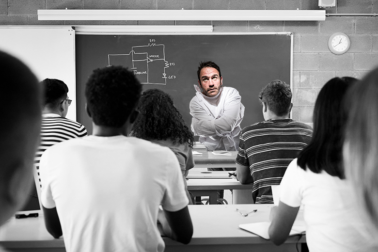 A teacher in class wearing a straitjacket. To illustrate that teaching-only contracts can potentially restrict academics from maintaining a living relationship with their subject. A teacher in class wearing a straitjacket. To illustrate that teaching-only contracts can potentially restrict academics from maintaining a living relationship with their subject.