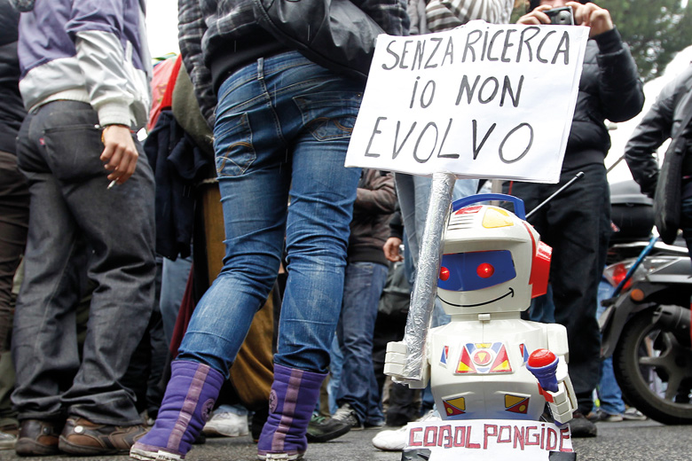 Toy robot holding 'Without research I can't evolve' sign, Italy