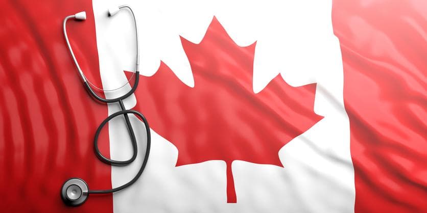 stethoscope lying on a Canadian flag, red-white-red stripes with a red maple leaf
