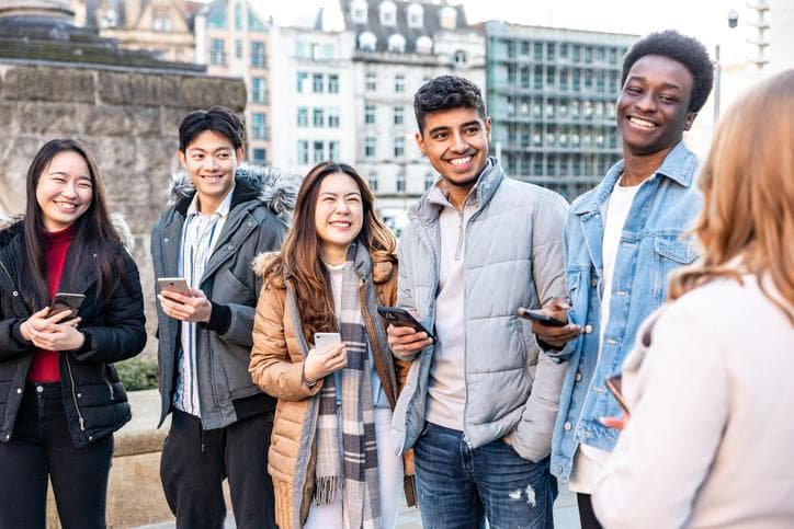 Happy group of friends in the city using mobile phones and laughing together