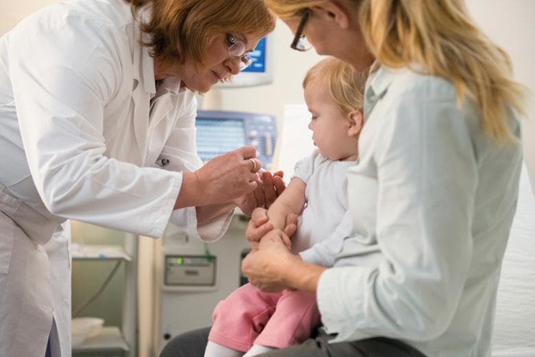 Female doctor administering vaccine to small child