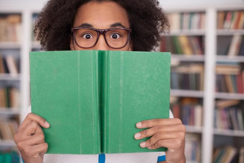 Student peeking behind book, Student Experience Survey 2016 university reviews