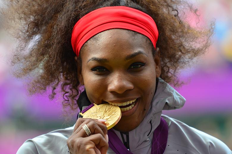 US Serena Williams poses on the podium with her gold medal after defeating Russia's Maria Sharapova in the women's singles gold medal match of the London 2012 Olympic Games, at the All England Tennis Club in Wimbledon, southwest London, on August 4, 2012. AFP PHOTO / LUIS ACOSTA (Photo credit should read LUIS ACOSTA/AFP/GettyImages)  