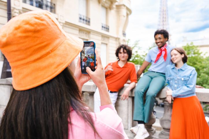 student taking a photo of friends in front of the Eiffel tower, all dressed in bright colours