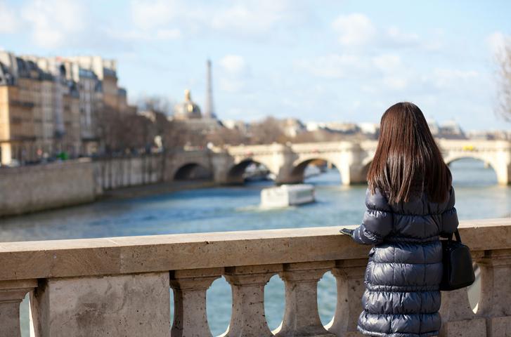 Alone brunette female in Paris, looking at the Seine